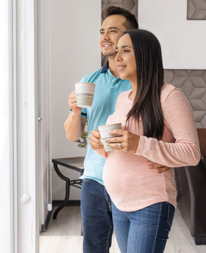 Husband and pregnant wife looking out the window.