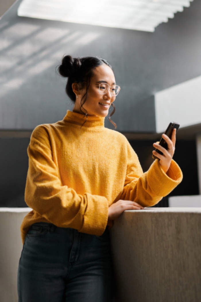 Young Asian woman smiling at her phone