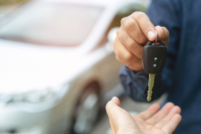 individual handing a car key to another