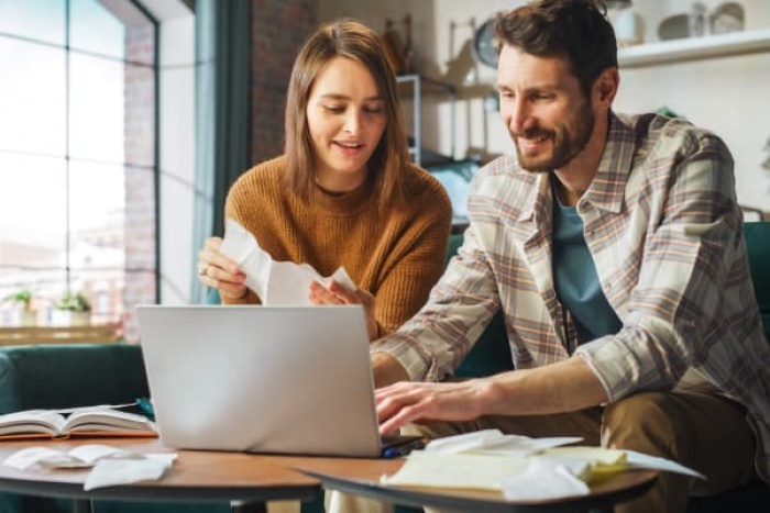 couple on couch paying bills with laptop