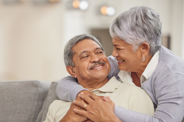 man sitting on couch with wife behind him looking into each others eyes