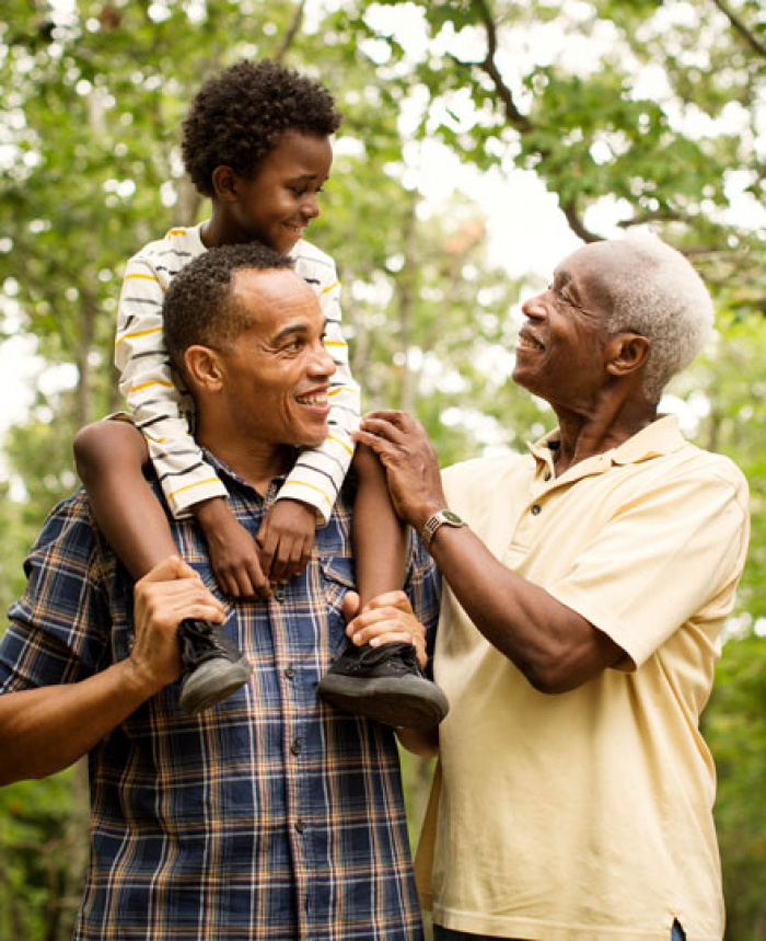 Three generations of men walking in the park with youngest on his fathers shoulders