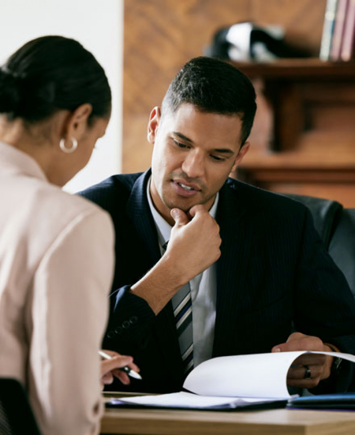 Woman signing document while businessman reviews