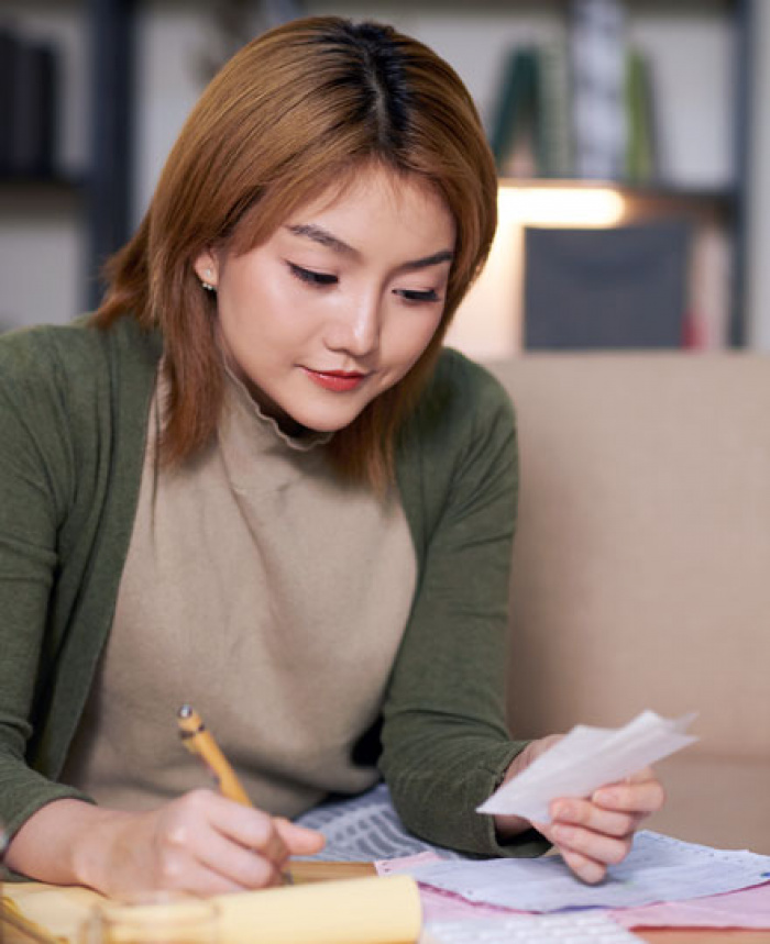 Woman on couch reviewing finances.