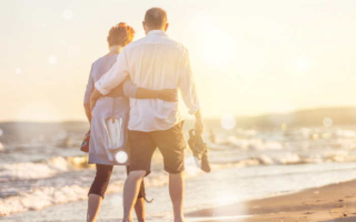 retired couple walking on beach