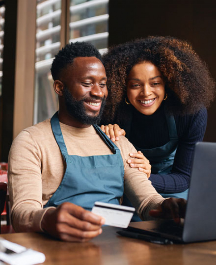 Restaurant owners sitting in front of laptop holding a credit card
