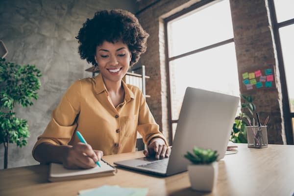 woman using laptop taking notes