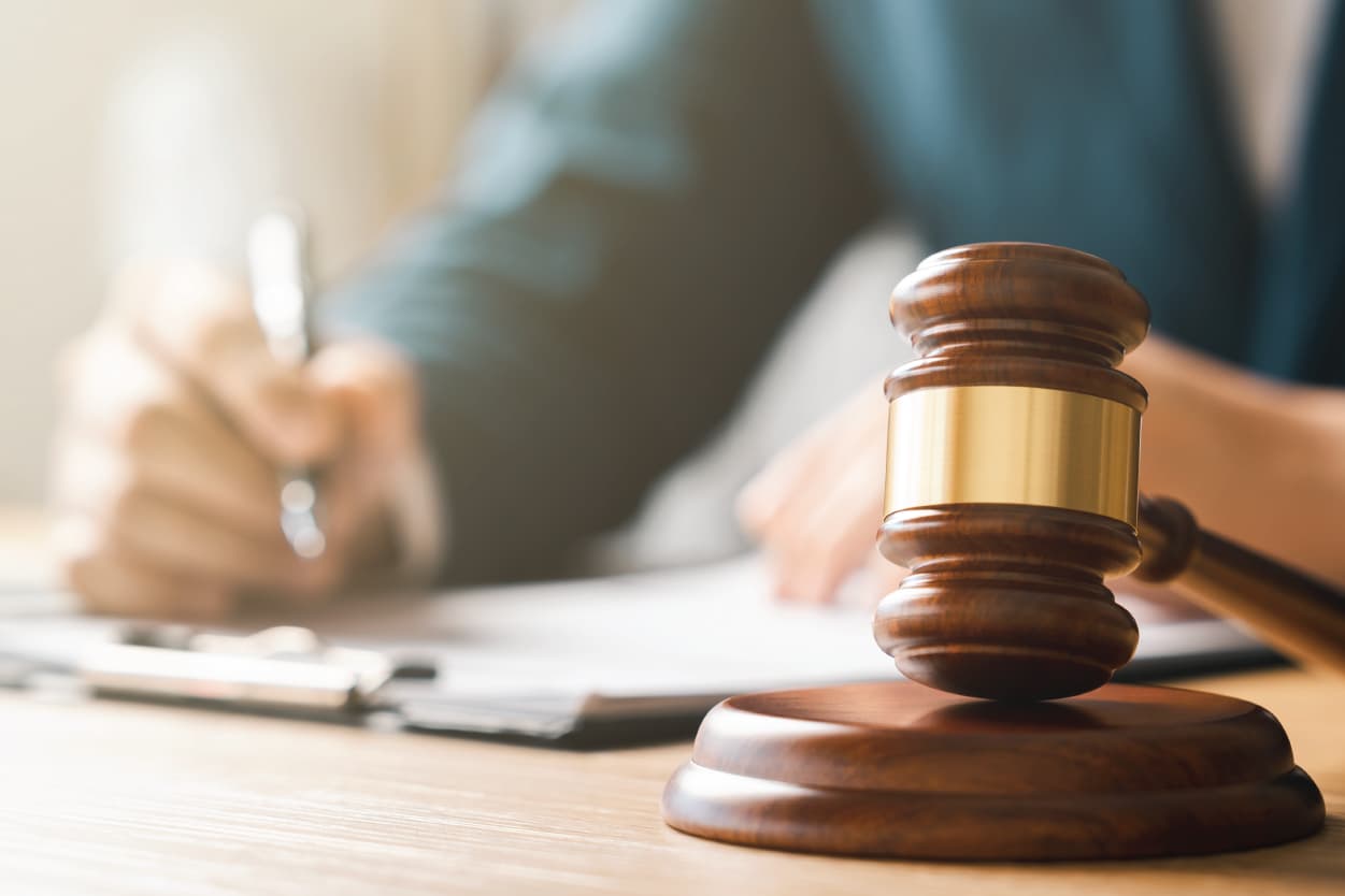 gavel in foreground with person writing on a pad behind it