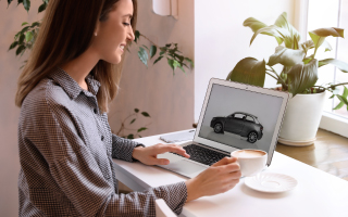 woman with a coffee shopping for a car on laptop