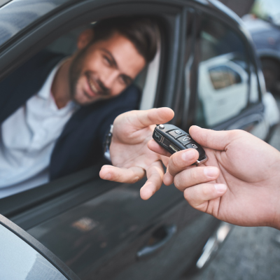 man in vehicle being handed car key fob