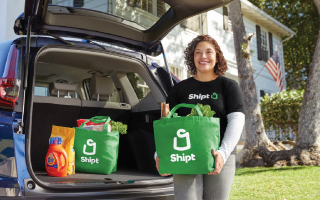 smiling woman unloading groceries from back of an SUV