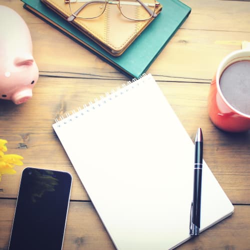 desk with notebook coffee phone piggy bank and more