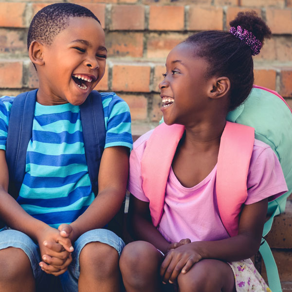 Two children with backpacks laughing
